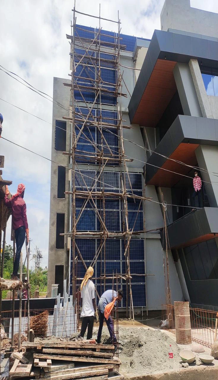 Workers installing wall-mounted solar panels on a building facade with scaffolding